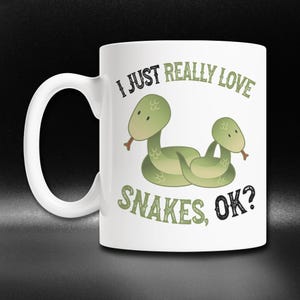 May include: White ceramic coffee mug with a green snake design and the text "I just really love snakes, ok?"