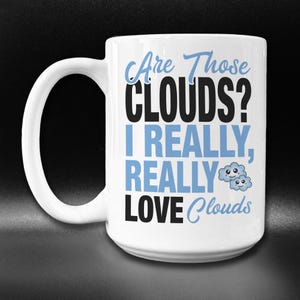 May include: White ceramic coffee mug with a black and blue design. The mug says "Are Those Clouds? I Really, Really Love Clouds" with two cartoon clouds with faces.