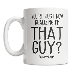 May include: White ceramic coffee mug with black text that reads "You're just now realizing I'm that guy?" with a small floral design at the bottom.