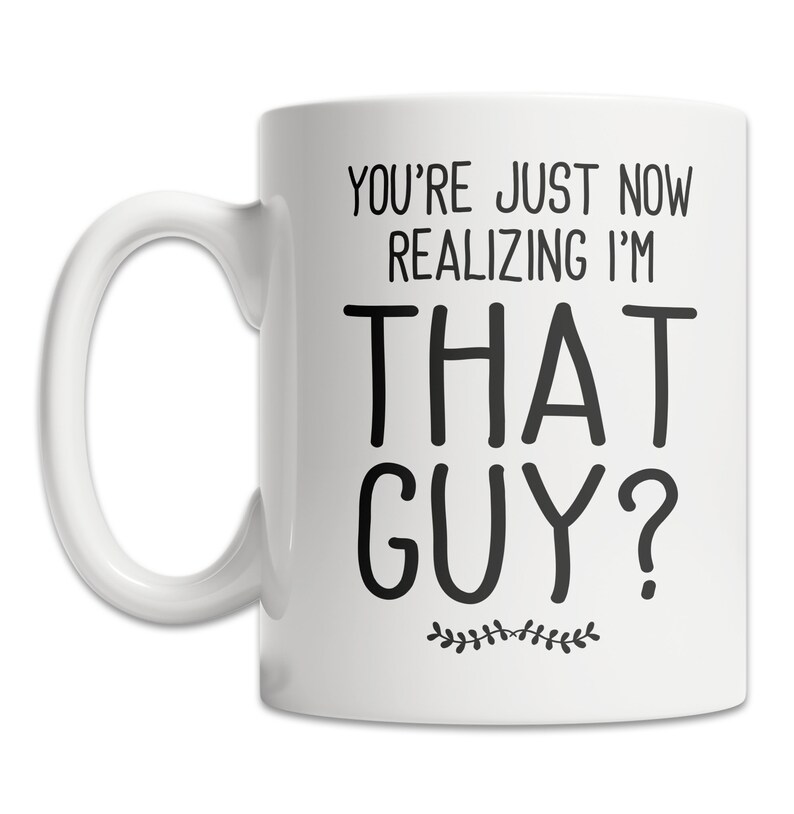 May include: White ceramic coffee mug with black text that reads "You're just now realizing I'm that guy?" with a small floral design at the bottom.
