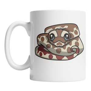 May include: White ceramic mug featuring a cartoon snake design. The snake is brown and tan with a red underbelly and large, friendly eyes. The mug has a curved handle and a glossy finish, suitable for hot or cold beverages.