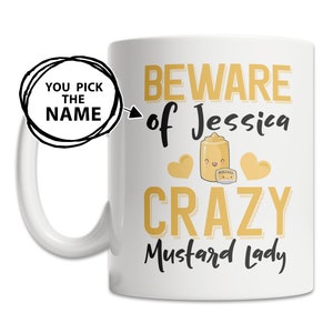 May include: White ceramic mug with a black outline of a mustard bottle with a smiling face and the text "Beware of Jessica Crazy Mustard Lady".