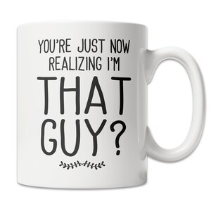 May include: White ceramic coffee mug with black text that reads "You're just now realizing I'm that guy?" with a small floral design at the bottom.