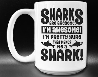 May include: White ceramic coffee mug with a black graphic that reads "Sharks are awesome. I'm awesome! I'm pretty sure that makes me a shark!"