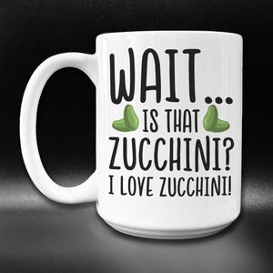 May include: White ceramic mug with a black and green design. The mug has the text "WAIT... IS THAT ZUCCHINI? I LOVE ZUCCHINI!" printed on it.