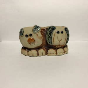 May include: Ceramic planter shaped like two dogs, one brown and one gray, with blue eyes and brown noses.
