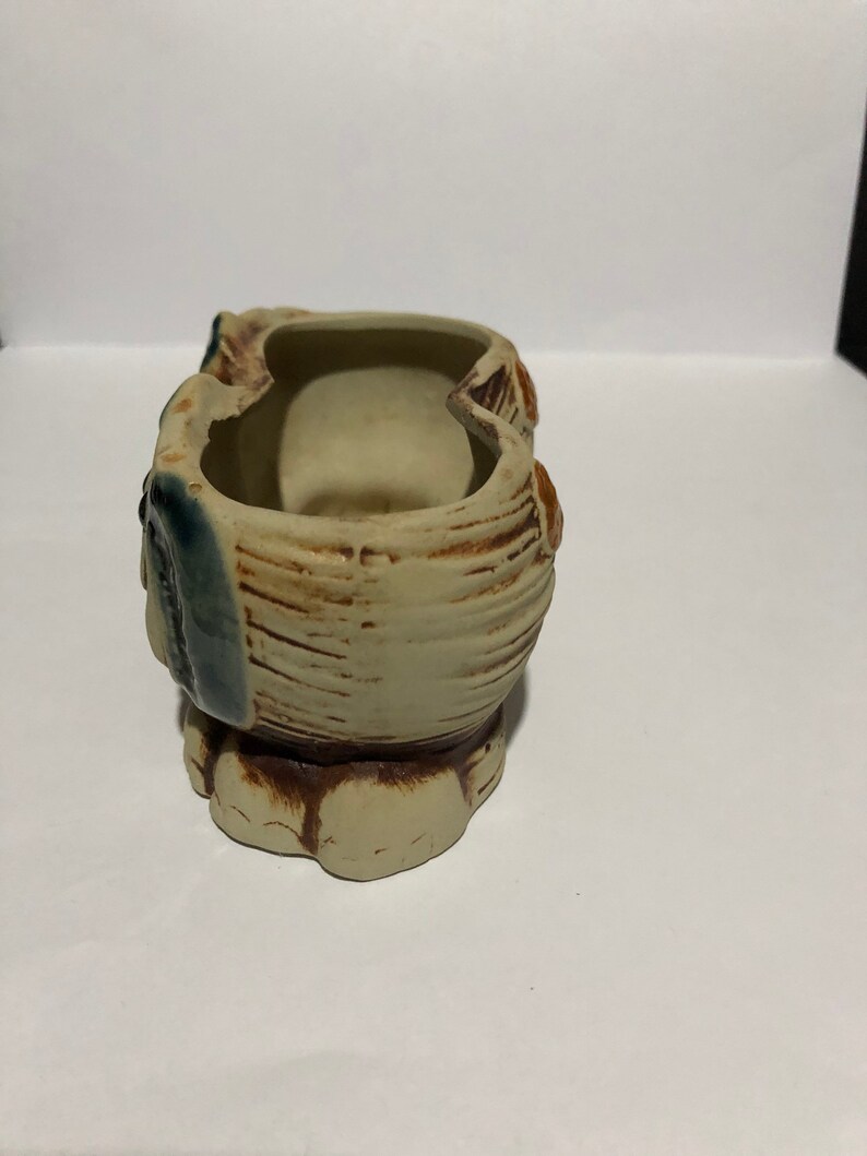 May include: A ceramic owl planter with two separate compartments. The owl is painted in shades of brown, beige, and blue. The planter has a textured surface and a rounded base.