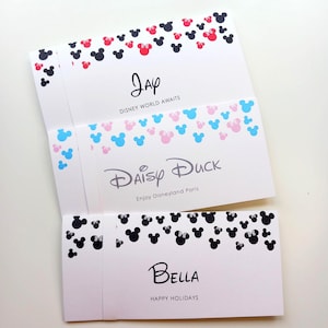 May include: Three white rectangular cards featuring black, red, blue, and pink mouse-ear silhouettes. The top card says Jay and Disney World Awaits. The middle card says Daisy Duck and Enjoy Disneyland Paris. The bottom card says Bella and Happy Holidays.