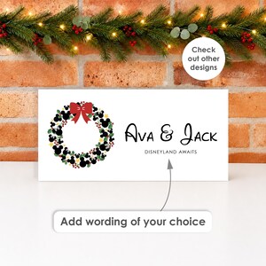 May include: A rectangular white sign featuring a holiday wreath made of black Mickey Mouse silhouettes, green holly leaves, and small yellow stars, topped with a red bow. The text reads "Ava & Jack" and "DISNEYLAND AWAITS" in black font.