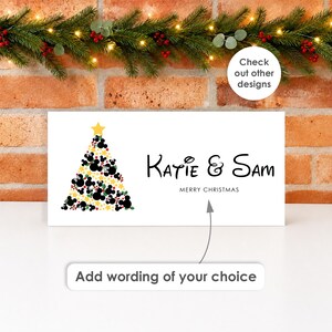 May include: A rectangular white sign featuring a Christmas tree graphic composed of black mouse-ear silhouettes, green leaves, red berries, and yellow stars, topped with a yellow star. The text reads Katie & Sam, MERRY CHRISTMAS, and Add wording of your choice.
