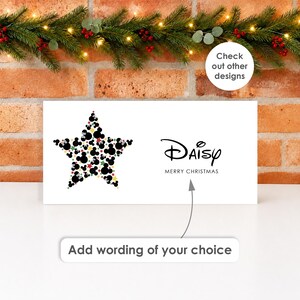 May include: A white rectangular sign featuring a star shape composed of black, red, and gold mouse-ear silhouettes. The text reads Daisy and Merry Christmas. An arrow points to a box with the text Add wording of your choice.