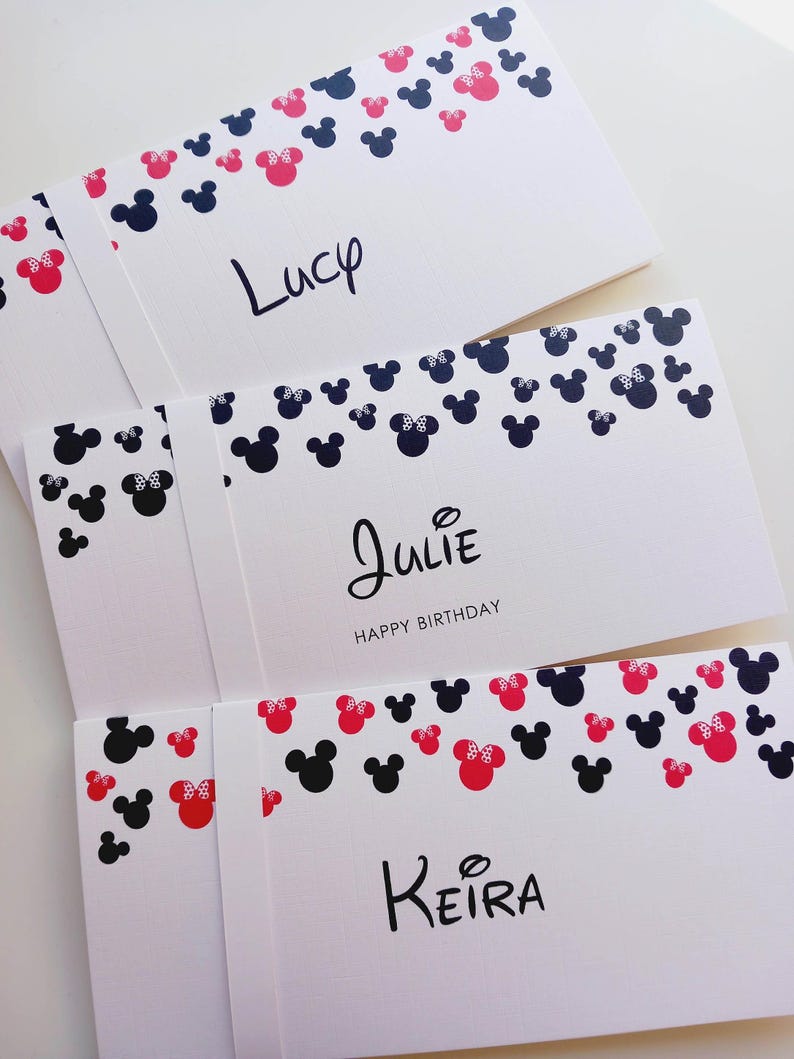 May include: Three white rectangular cards featuring a pattern of black and pink mouse head silhouettes along the top edge. The cards are personalized with the names Lucy, Julie, and Keira in black script, with Happy Birthday printed below Julie.