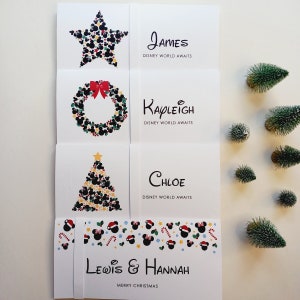 May include: Four white rectangular cards featuring festive holiday graphics made of black mouse-ear silhouettes. The cards display the names James, Kayleigh, Chloe, and Lewis & Hannah, with the text Disney World Awaits or Merry Christmas printed.