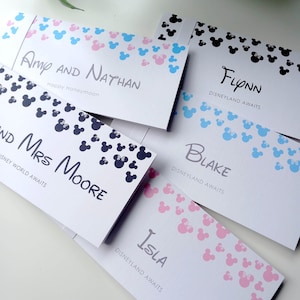 May include: Five rectangular white paper envelopes featuring various patterns of small mouse-ear silhouettes in pink, blue, and black. Each envelope is personalized with names such as Amy and Nathan, Flynn, Mrs. Moore, Blake, and Isla, along with text like Disneyland Awaits.