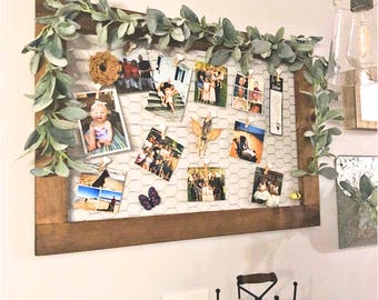 May include: A rustic wooden framed wire mesh board with a garland of faux greenery. The board is decorated with photos and other small items. The text "Customer photo: Danielle 22x32 Provincial frame Ellie Eclectic Shop" is visible at the bottom of the image.