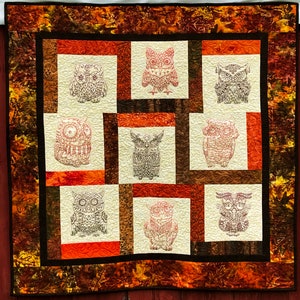 May include: A quilt with a brown and orange patchwork design featuring nine embroidered owls. The owls are all different designs and are surrounded by a brown and orange border.
