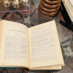 May include: An open book with a yellowed page, titled "Les Humeurs Constituantes" and "Le Sang." The text is in French and discusses the components of blood.