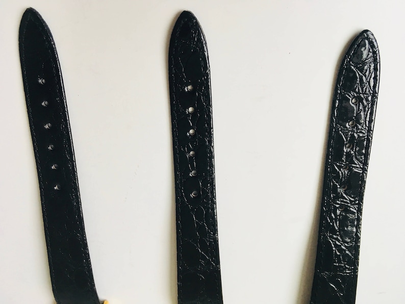 May include: Three black watch straps with varying textures and designs. The straps are made of a leather-like material and have holes for adjustment. The straps are displayed against a white background.