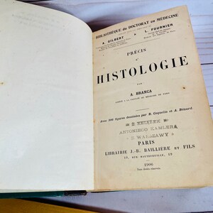 May include: A vintage book titled "Precis d'Histologie" by A. Branca. The book is part of a medical library series and features illustrations by R. Coquelin and A. Benard. It was published in Paris in 1906 by J.-B. Bailliere et Fils.