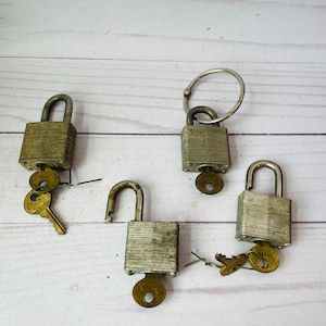 May include: Four silver padlocks with keys. The padlocks are all closed and have a silver finish. The keys are all different sizes and shapes.