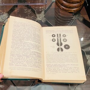 May include: An open book with a diagram of a human nerve cell. The book is titled "La Fibre Nerveuse" and is written in French. The text describes the structure of the nerve cell and its function.