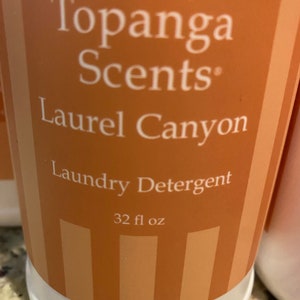 May include: A 32 fl oz bottle of Topanga Scents Laundry Detergent in Laurel Canyon scent. The bottle is orange with white stripes and white text.