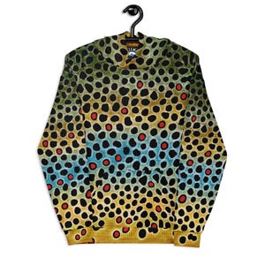 May include: A hooded sweatshirt with a brown trout pattern. The design features a repeating pattern of black spots with red and yellow accents over a blue and yellow background. The sweatshirt is hanging on a black hanger.