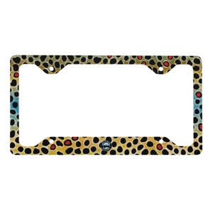 May include: License plate frame with a brown trout pattern. The frame features a repeating pattern of black spots, red dots, and yellow-brown hues, with a blue and green gradient on the left side. A small emblem is centered at the bottom.