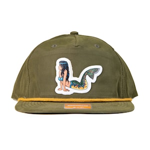 Könnte beinhalten: Eine grüne Baseballkappe aus Canvas mit gelber Kordel und einem Aufnäher einer Meerjungfrau mit Fischschwanz.