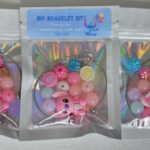 May include: DIY bracelet kits in clear plastic bags. Each kit contains colourful beads, a pink character charm, and a silver-tone bracelet base. The kits are labelled with the text "DIY BRACELET KIT!" and "Thanks for celebrating with me!"