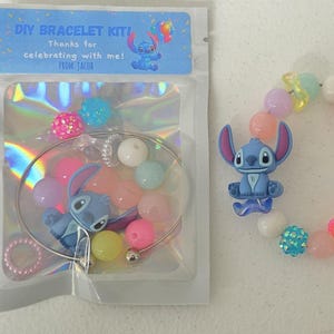 以下が含まれることがあります： 青と白のスティッチのキャラクターが付いたDIYブレスレットキット。キットには、ブレスレット、さまざまな色のビーズ、スティッチチャームが含まれています。パッケージには「DIY BRACELET KIT！私と一緒にお祝いしてくれてありがとう！From：JACOB」と書かれています。