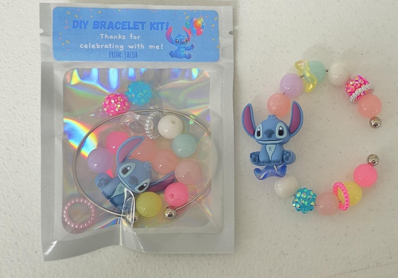 以下が含まれることがあります： 青と白のスティッチのキャラクターが付いたDIYブレスレットキット。キットには、ブレスレット、さまざまな色のビーズ、スティッチチャームが含まれています。パッケージには「DIY BRACELET KIT！私と一緒にお祝いしてくれてありがとう！From：JACOB」と書かれています。
