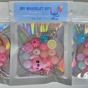May include: DIY bracelet kits in clear plastic bags. Each kit contains a pink Stitch character charm, colourful beads, and decorative elements. The kits are designed for making bracelets and feature a variety of pastel colours.