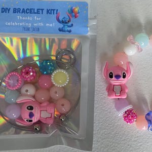 May include: A DIY bracelet kit with a blue label reading "DIY BRACELET KIT! Thanks for celebrating with me! From Jacob." The kit contains a bracelet wire, pink, blue, and yellow beads, and a pink character charm. A finished bracelet is also shown.