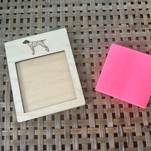 May include: A wooden picture frame with a cutout of a German Shorthaired Pointer dog. The frame has a blank space for a note or photo. A pink sticky note is next to the frame.