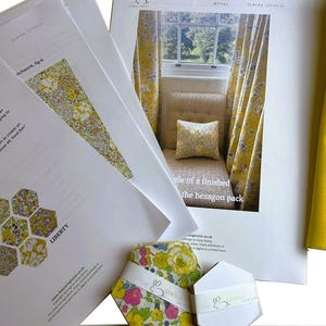 Peut inclure: Plusieurs tutoriels de couture, des échantillons de tissu et un paquet de tissu hexagonal. Les papiers présentent des motifs floraux et le mot "LIBERTY". Un échantillon de tissu jaune est également visible.