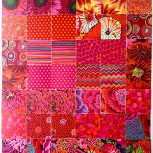 May include: A patchwork quilt made of various red, pink, and orange fabrics with floral, geometric, and polka dot patterns.