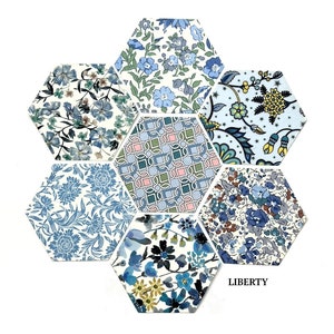 May include: Six hexagonal fabric swatches in various blue floral patterns, arranged in a honeycomb shape. The fabric is white with blue floral designs. The word "LIBERTY" is printed in black at the bottom of the image.