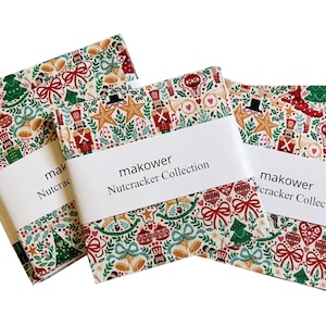 May include: Three stacks of fabric squares from the Makower Nutcracker Collection, featuring a festive pattern of nutcrackers, Christmas trees, stars, bells, and bows in red, green, and gold on a cream background, wrapped in white paper bands.
