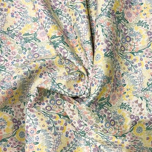 May include: A white fabric with a floral pattern in shades of yellow, pink, blue, and green. The fabric is a cotton blend and is ideal for quilting, sewing, and crafting.