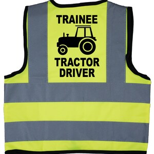 May include: Yellow and grey safety vest with reflective stripes. The vest has a black patch with the text "Trainee Tractor Driver" and a black silhouette of a tractor.