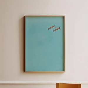 Könnte beinhalten: Ein gerahmter Druck einer minimalistischen Illustration von zwei Figuren, die in einem türkisblauen Gewässer schwimmen.