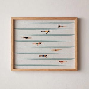 以下が含まれることがあります： プールで泳ぐ人を描いたフレーム入りのアートプリント。水着姿の人物が複数描かれており、それぞれ異なるレーンに配置されています。背景には水平の青い線があり、フレームは明るい色の木材でできています。