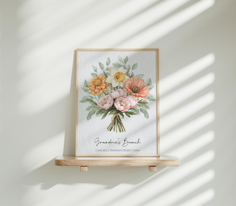 May include: A framed print with a watercolor illustration of a bouquet of flowers in shades of pink, orange, and yellow. The flowers are arranged in a vase and the print has the text "Grandma's Bunch" and the names "Chelsea, Hannah, Sean, Gina".