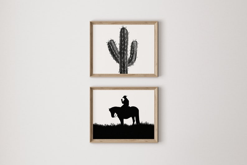 May include: Two framed black and white prints. The top print features a silhouette of a cactus. The bottom print features a silhouette of a cowboy riding a horse.