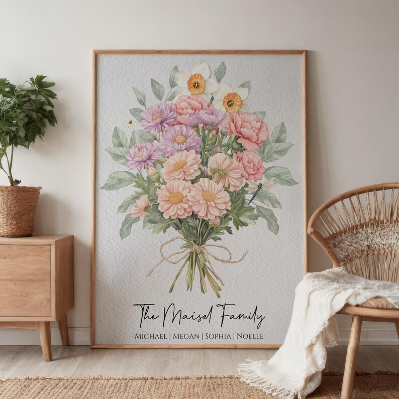 Op de afbeelding: Een ingelijste bloemenprint met een aquarelboeket van roze, perzik en paarse bloemen en groene bladeren. De tekst "The Maisel Family" staat boven de namen Michael, Megan, Sophia en Noelle.
