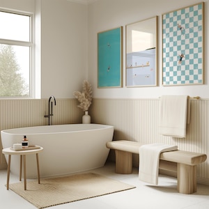 K&ouml;nnte beinhalten: Eine wei&szlig;e Badewanne mit einem schwarzen Wasserhahn, eine Holzbank mit einem wei&szlig;en Handtuch und drei gerahmte Drucke von Schwimmern in einem Pool an einer Wand mit Holzverkleidung.