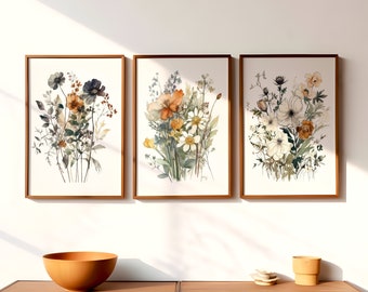 May include: Three framed watercolor paintings of floral bouquets. The first painting features a bouquet of orange, white, and blue flowers. The second painting features a bouquet of orange, white, and green flowers. The third painting features a bouquet of white and green flowers.