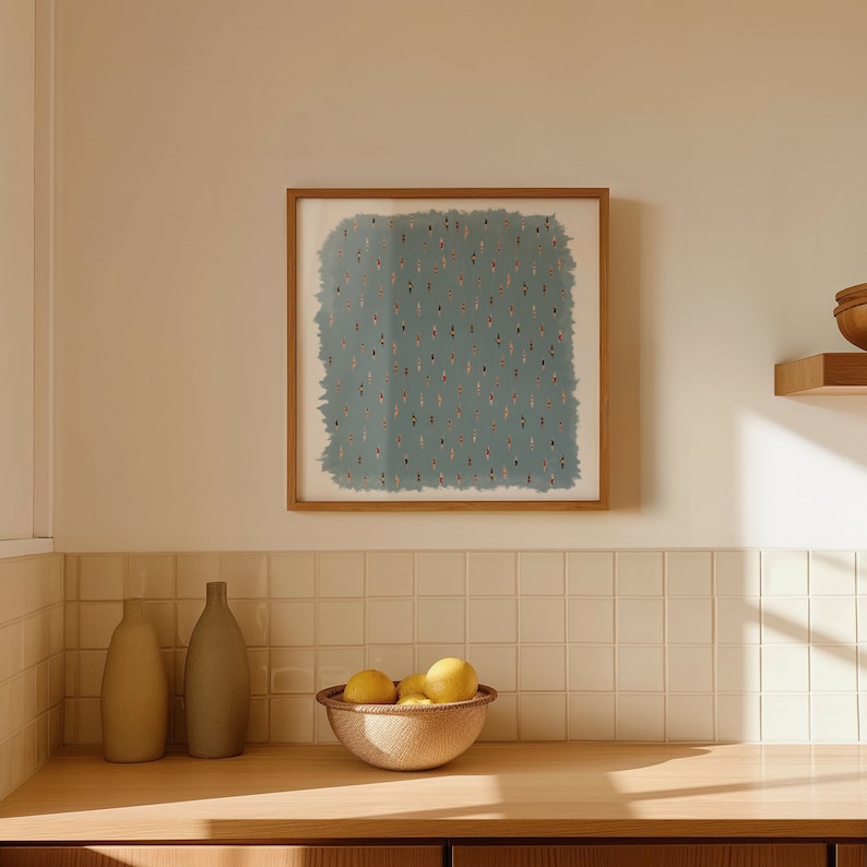 May include: A framed artwork with a blue background and a pattern of small, colorful figures. The artwork is hanging on a white tiled wall above a wooden countertop with two ceramic vases and a bowl of lemons.