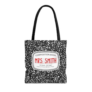 May include: Black and white tote bag with a composition book design. The bag has a red title that says "MRS. SMITH" and the text "COMPOSITION BOOK" in black. The bag also includes the text "100 Sheets 200 Pages 9 1/8 in x 7 1/8 in (24.7cm x 19cm)".